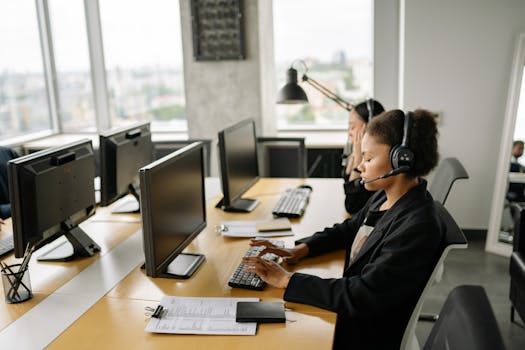 Customer support agents working at a call center with computers and headsets, focusing on tasks.