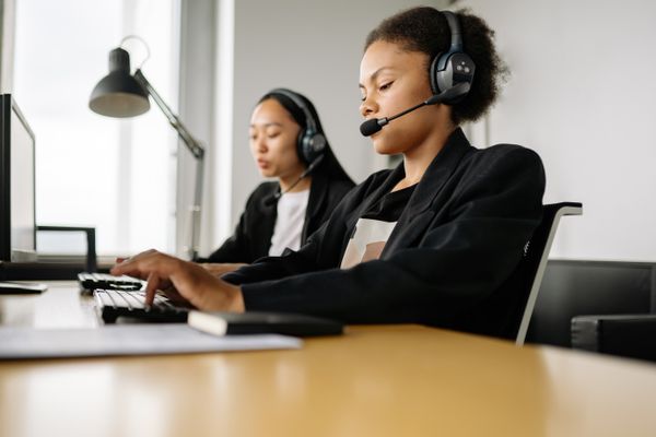 Two agents working at a support desk in headsets — photo by Yan Krukau on Pexels