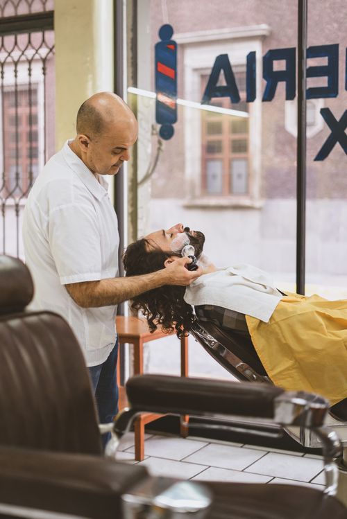 Free A professional barber shaving a customer's beard in a stylish barber shop setting. Stock Photo