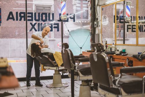 Free A barber expertly shaves a client's face in a classic barbershop setting. Stock Photo