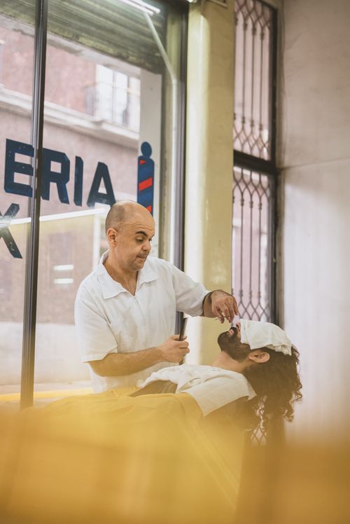 Free Barber skillfully shaving a customer in a cozy barbershop with a relaxing atmosphere. Stock Photo