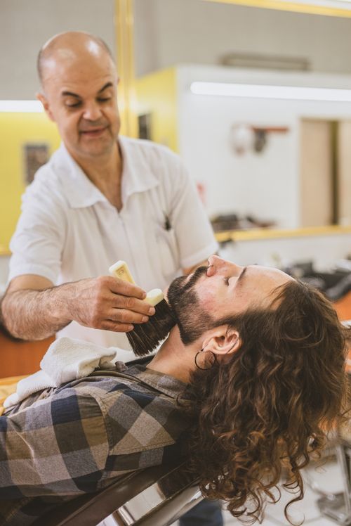 Free A barber skillfully grooms a man's beard in a modern barber shop setting. Stock Photo