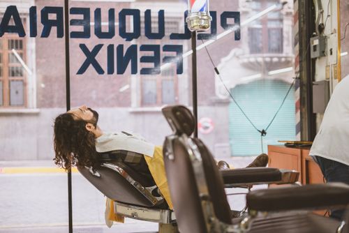 Free A man relaxes in a vintage barber chair in a classic barbershop setting. Stock Photo