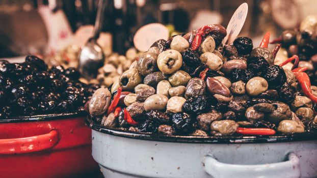 A colorful assortment of olives and red peppers showcased in market stalls.