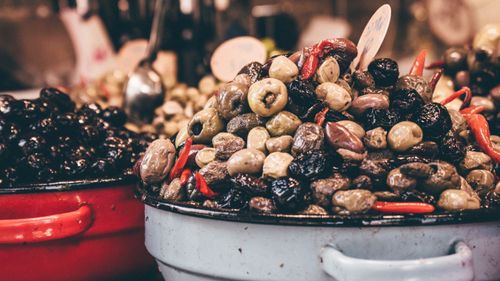 Free A colorful assortment of olives and red peppers showcased in market stalls. Stock Photo
