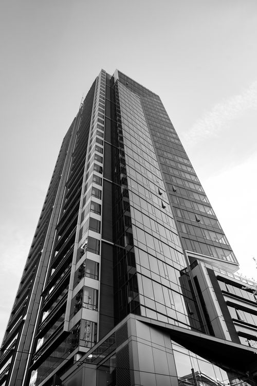Free Black and white image of a modern skyscraper with glass windows seen from below, showcasing urban architecture. Stock Photo