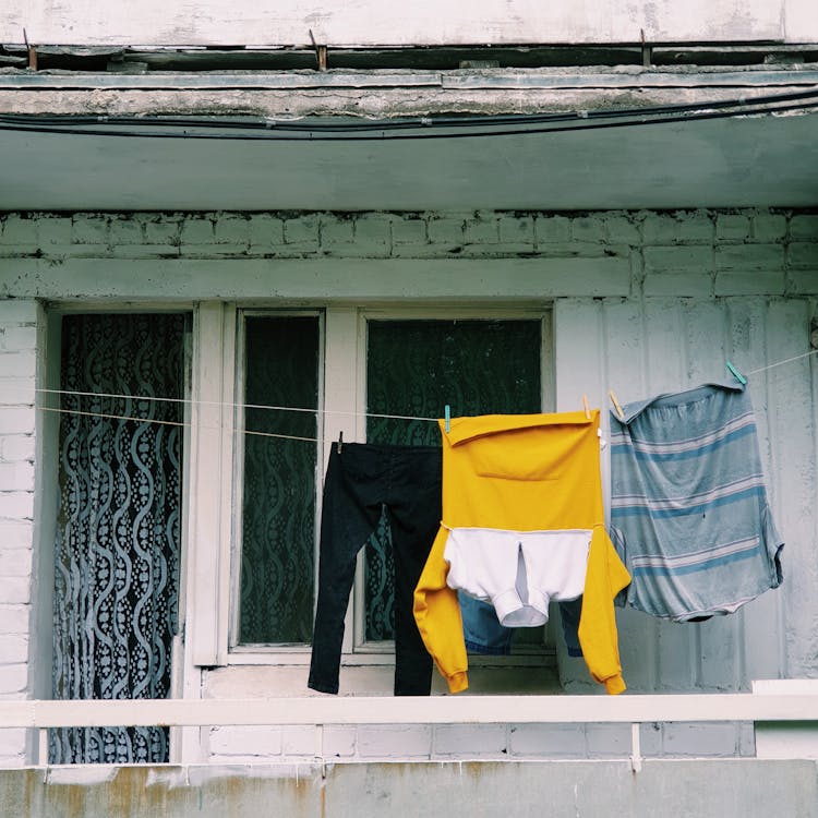 A woman hanging out her washing on a clothesline on her balcony