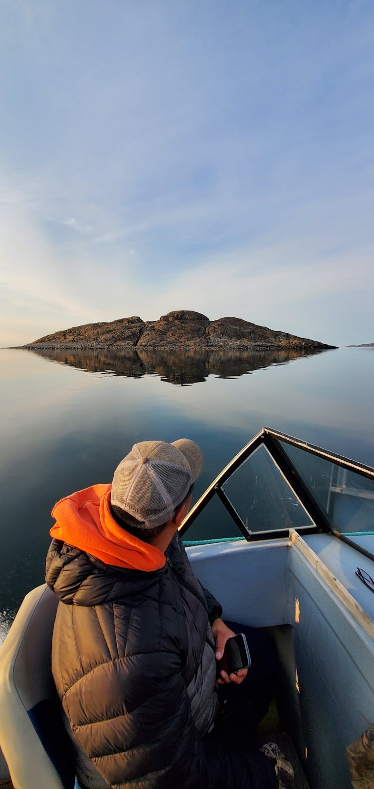 Person Wearing A Cap Looking At A Big Rock Formation On Water 