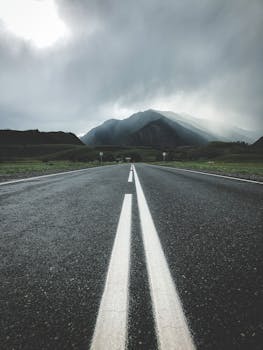 A scenic highway leading to the Altai Mountains under a moody, cloudy sky, offering a sense of adventure and tranquility.