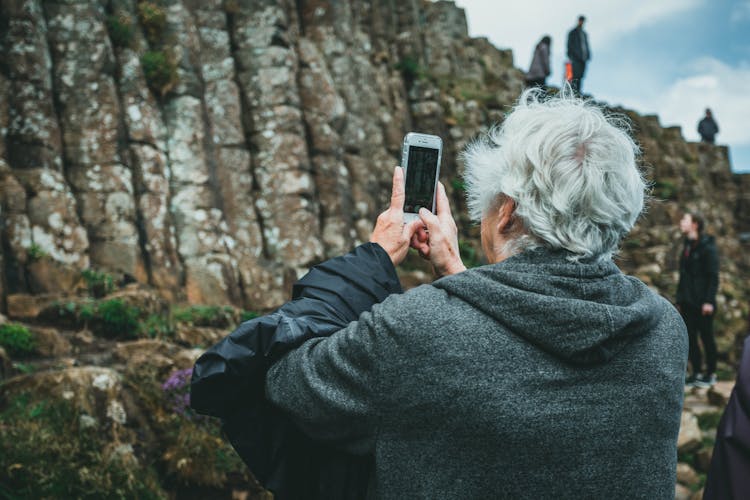 Old Man Taking Picture On Cell Of Cliff