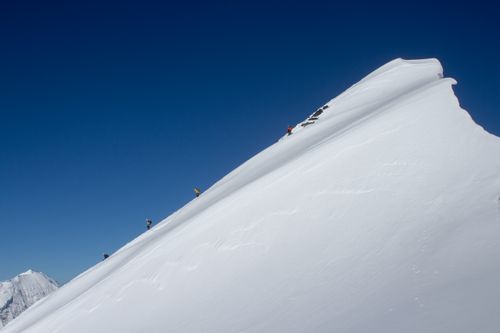Free Daring climbers scaling a snow-laden mountain slope under a clear blue sky in winter. Stock Photo
