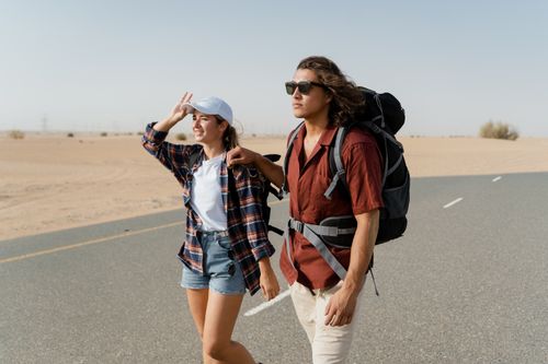 Free Young couple backpacking through a desert road, capturing wanderlust and exploration. Stock Photo