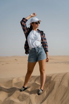 Stylish woman posing confidently in a sunny desert landscape, embracing adventure.