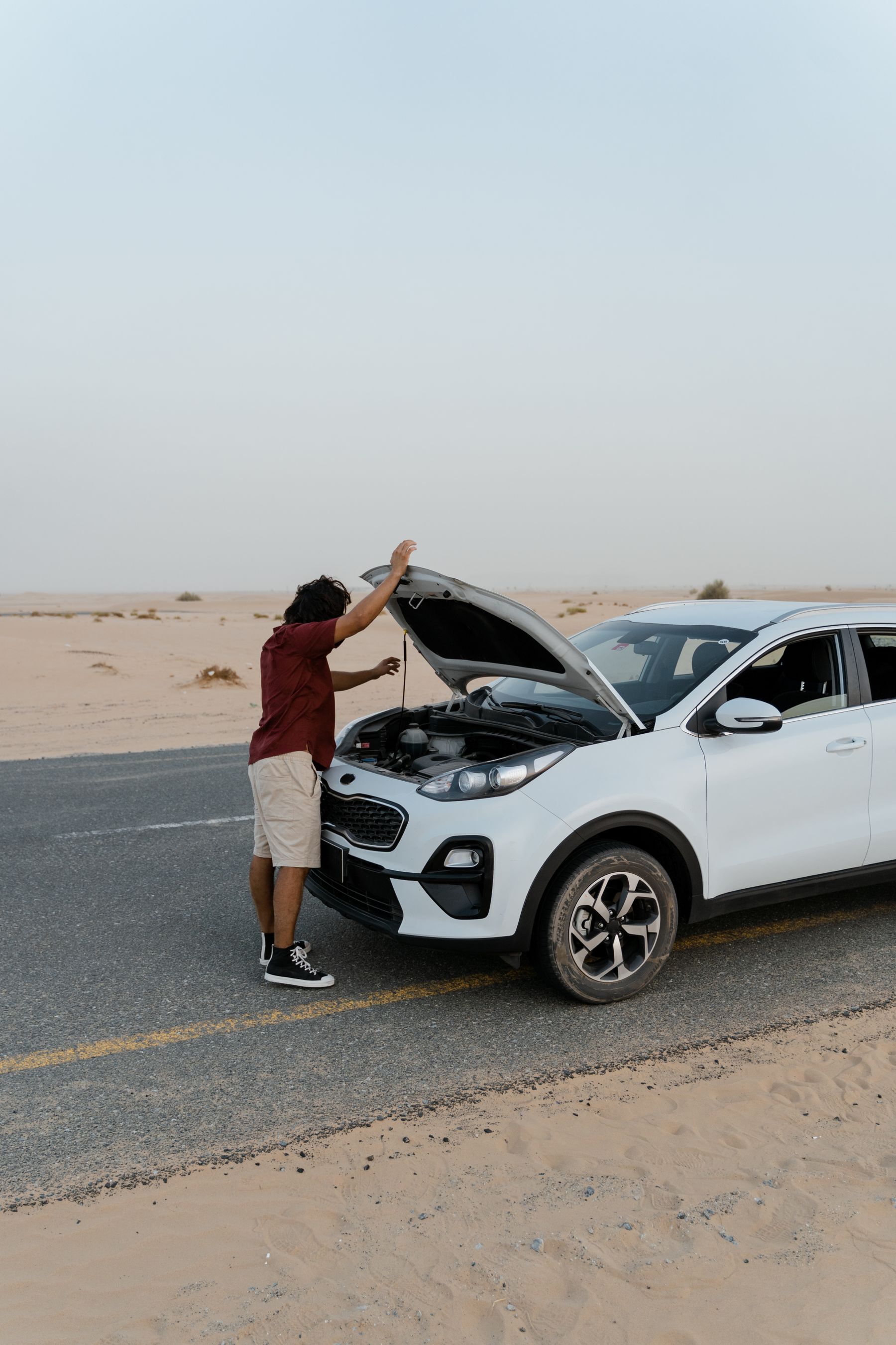 Driver checking a car with the hood open on the roadside