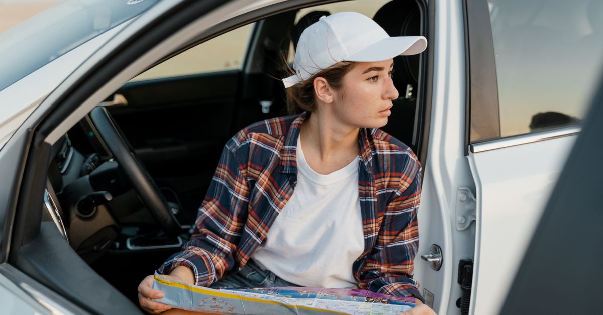Young woman in car with map, ready for road adventure.