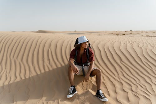 Man Sitting on Brown Sand