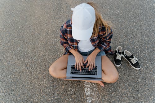 Overhead Shot of Woman Sitting on the Ground While Using a Laptop