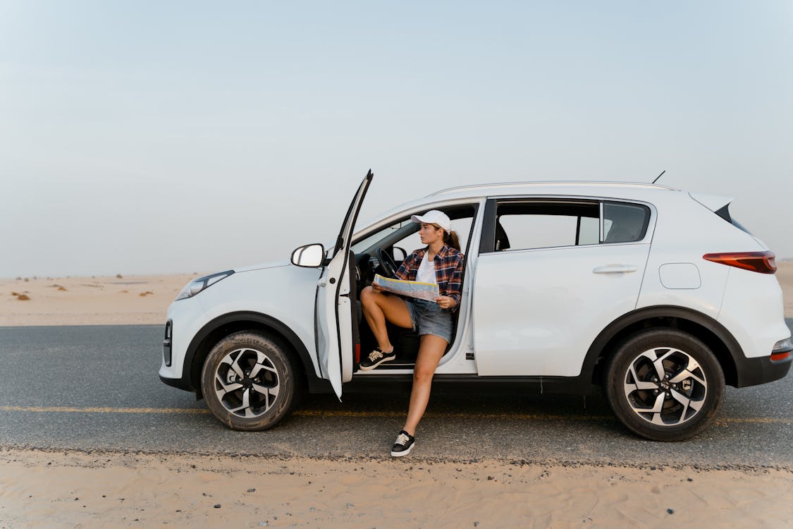 Free Woman Holding a Map While Inside a White Car Stock Photo