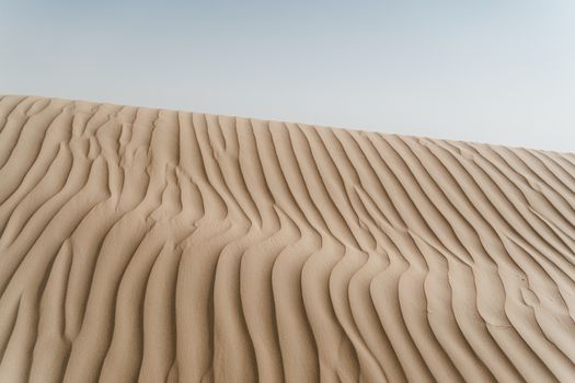 Captivating image of pristine sand dunes showcasing natural patterns and textures in a serene desert landscape.