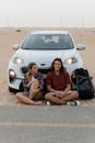 Man and Woman Sitting on the Road In Front of a Car