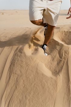 Close-up of a person running on desert sand, creating dynamic motion.