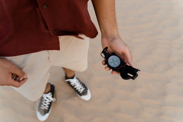 Person In The Desert Holding A Black Compass