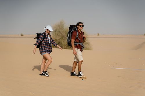 Free A couple hiking through an arid desert landscape with backpacks and casual attire. Stock Photo