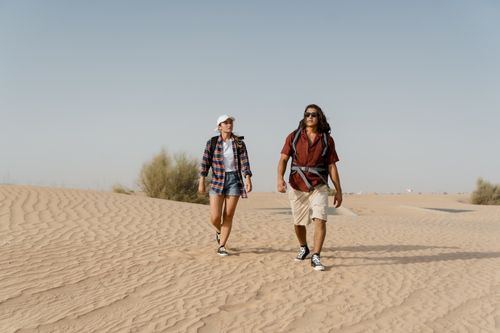 Free Couple exploring sand dunes in casual wear on a sunny day. Stock Photo