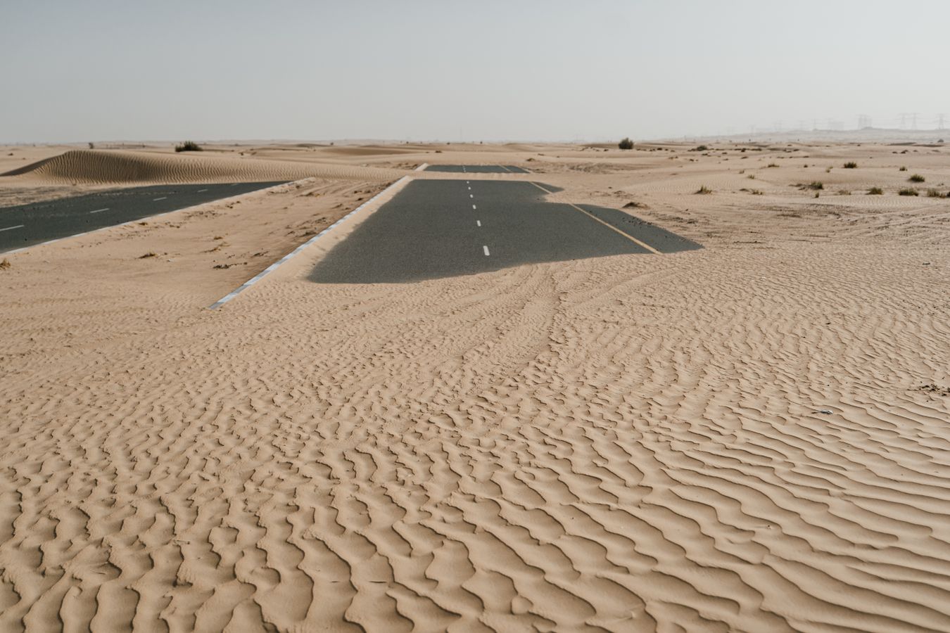 A desert road cutting through the sand dunes near the UAE border
