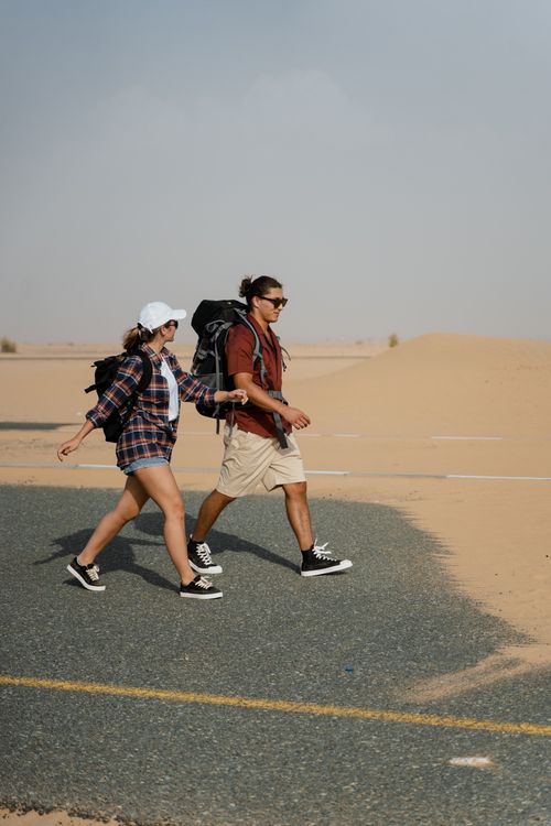 Free Young couple trekking through a desert road, embodying adventure and exploration. Stock Photo