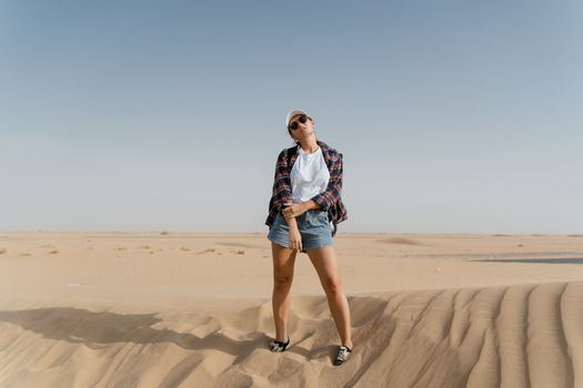 Woman posing in the desert with a casual outfit and clear sky background.