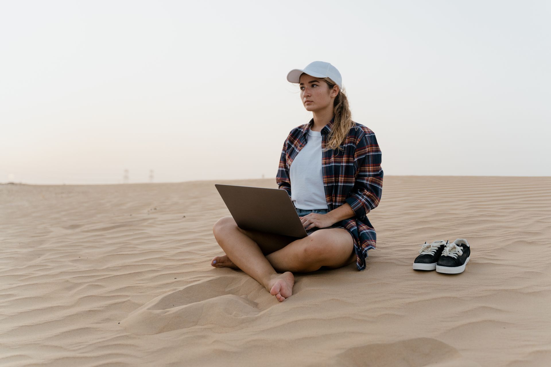 A woman working on a laptop in the desert. Ideal for remote work and travel themes.