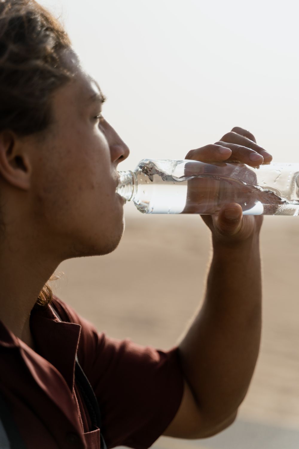 Close-up of a man drinking water from an insulated bottle outdoors