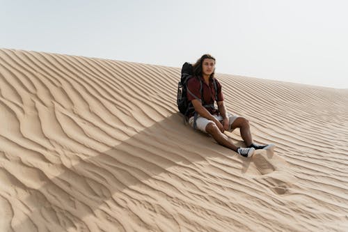 Man with a Backpack Sitting on Sand