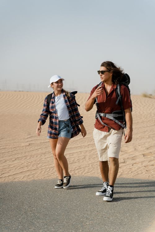 Free A man and woman hiking together in a sunny desert, enjoying an adventure. Stock Photo