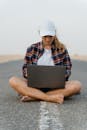 Woman in White Cap and Plaid Shirt Using a Laptop Computer