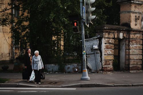 Free Elderly women standing at a crosswalk with a red stoplight in an urban setting. Stock Photo