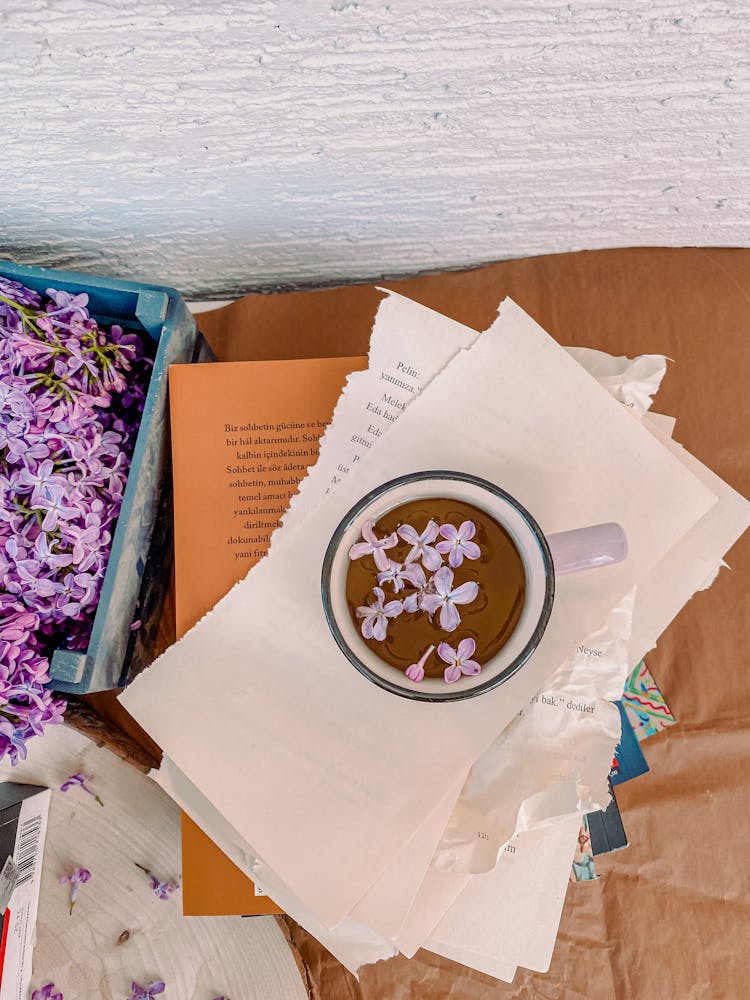 A Cup Of Beverage On Top Of Torn Pages Of A Book