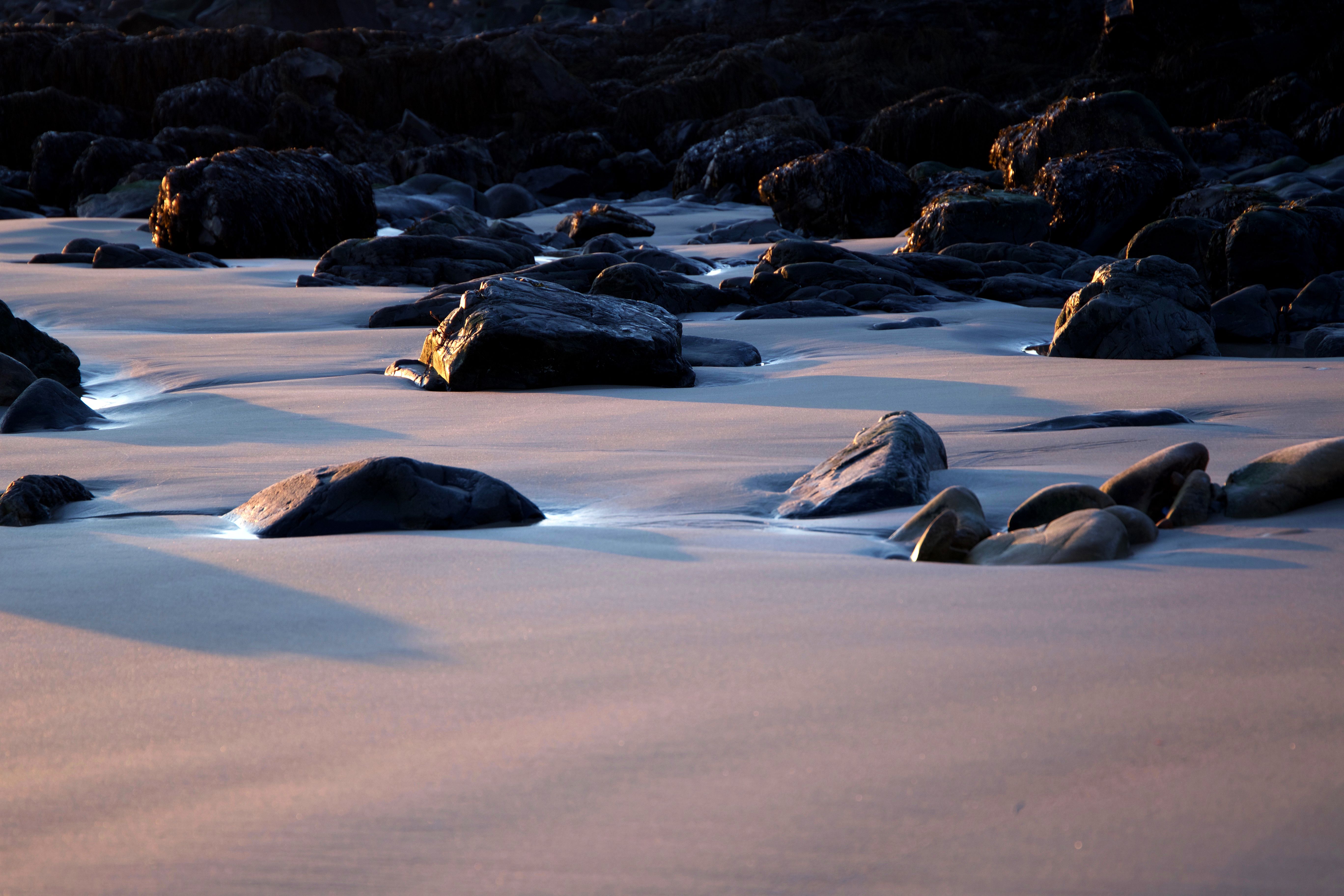 Black Rocks on Sand during Daytime · Free Stock Photo