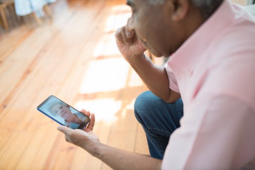 A man indoors video calling a woman using a smartphone. Bright light and warm atmosphere.