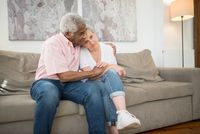 A senior couple embracing tenderly on the sofa at home.
