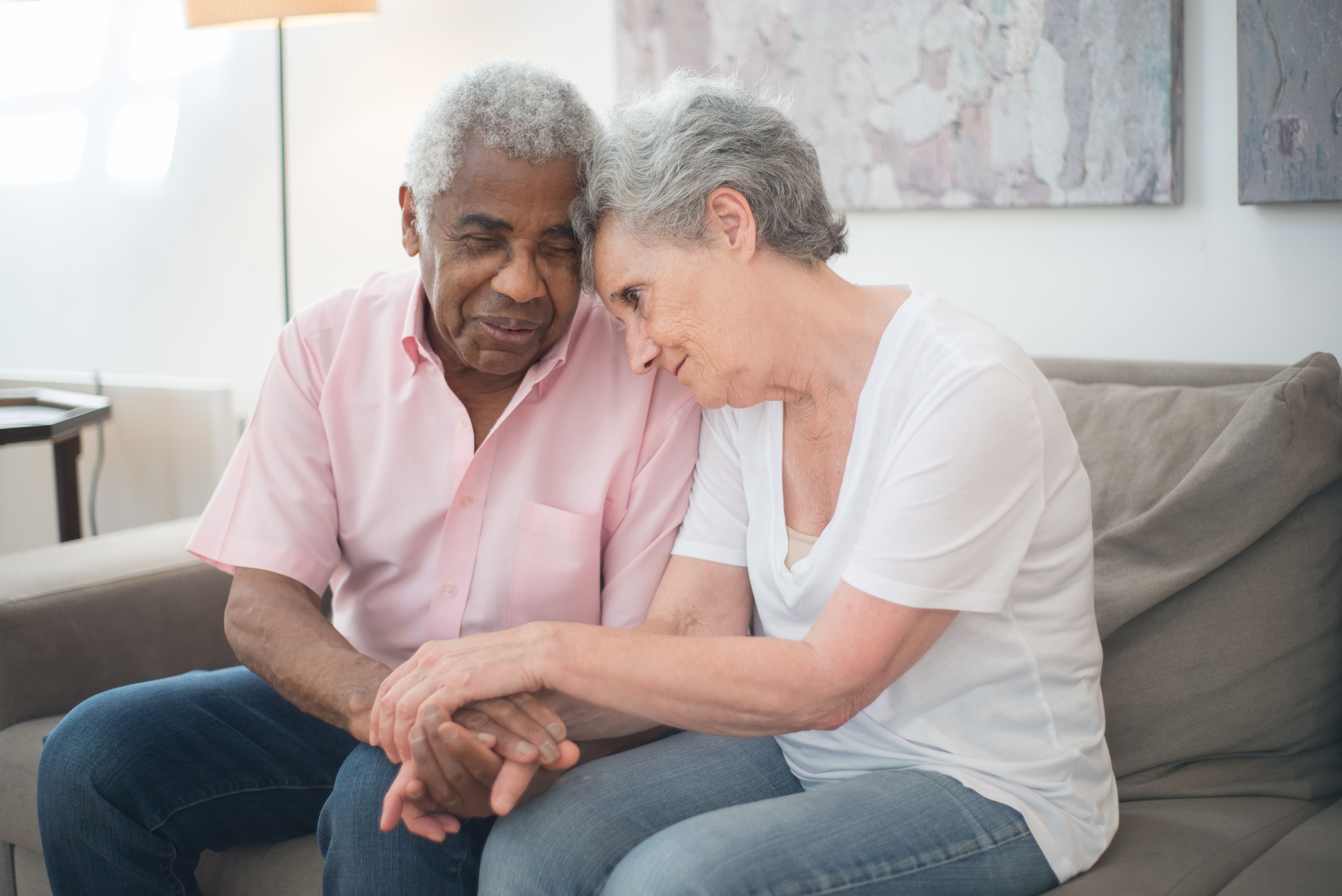 Caregiver warmly holding an elderly patient's hands in a sunlit living room