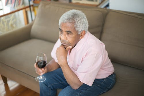 Elderly Man in Pink Button Up Shirt Holding a Glass of Wine