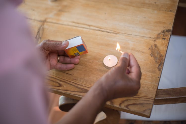 A Person Lighting A Candle