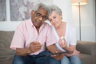 Elderly Man in Pink Button Up Shirt Holding a Candle With Elderly Woman in White V Neck T Shirt