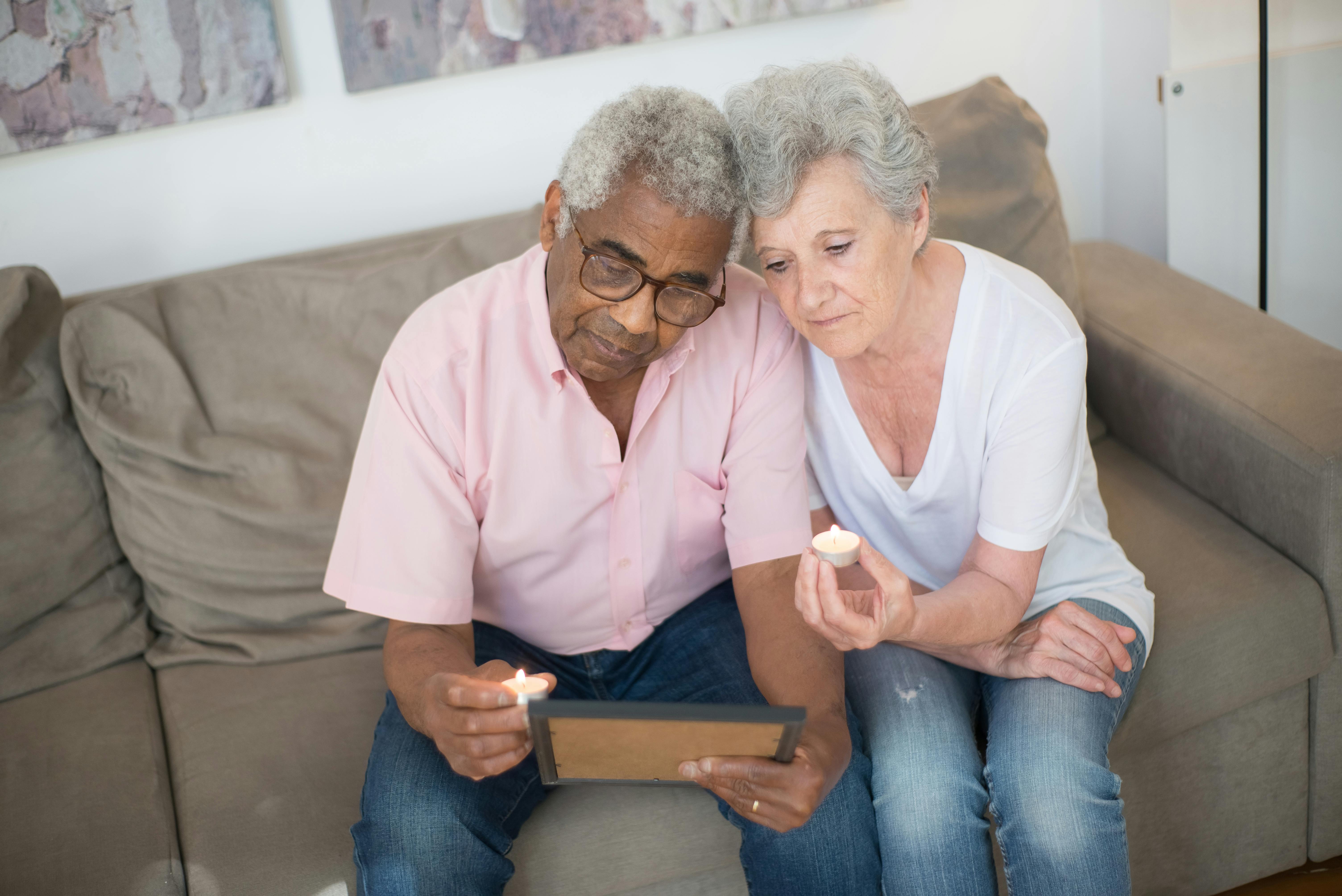 elderly couple sitting on sofa while looking at a picture frame