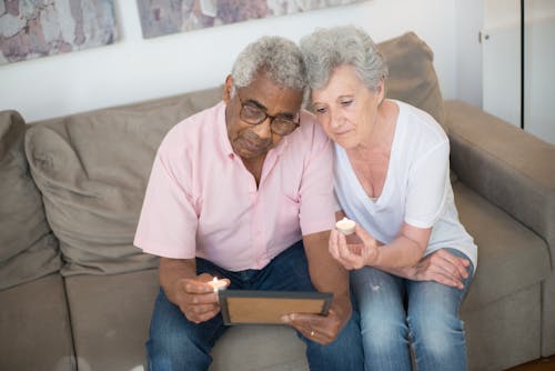 Elderly Couple Sitting on Sofa While Looking at a Picture Frame