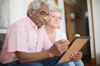 Man and Woman Holding Candles While Looking at a Picture Frame