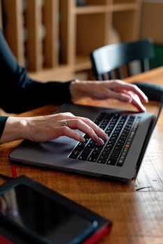A woman typing on a laptop at a wooden desk inside a cozy space.