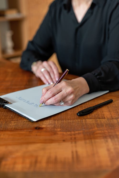 A Person Writing on a Piece of Paper on a Clipboard